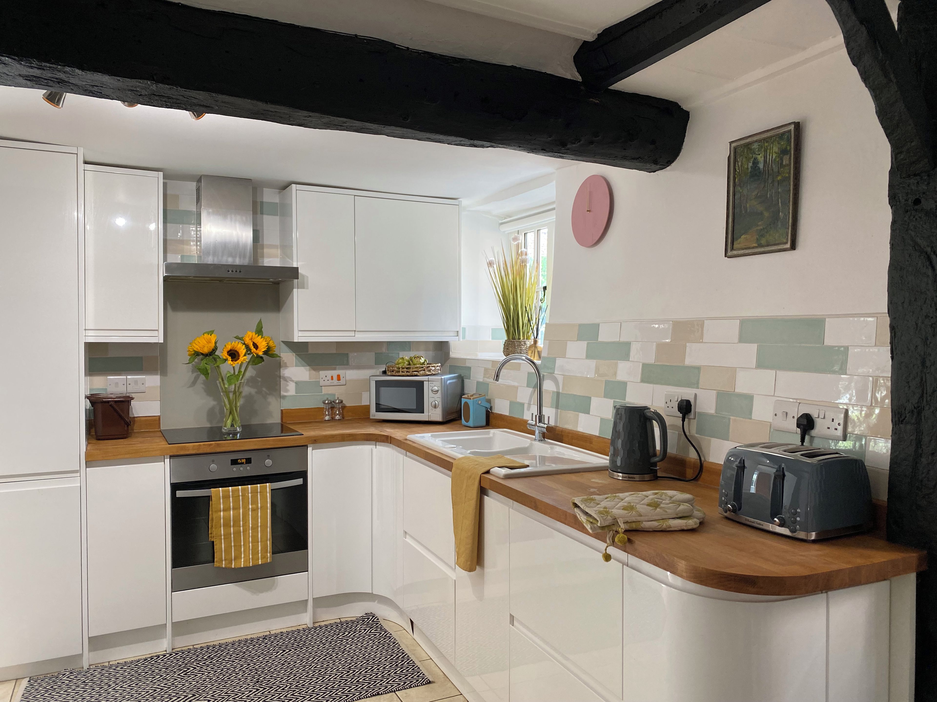 A modern kitchen with white cabinets, a built-in oven, a microwave, and a toaster.