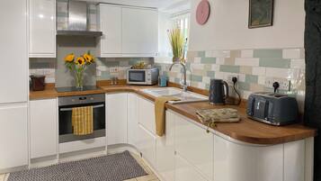 A modern kitchen with white cabinets, a built-in oven, a microwave, and a toaster.