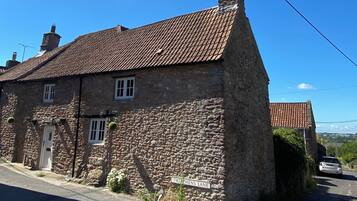 A stone building with a tiled roof, a visible chimney, and a street sign indicating 'TWECHENS LANE.'