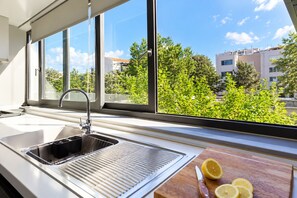 Une cuisine avec une grande fenêtre, un évier et une planche à découper ornée de tranches de citron.