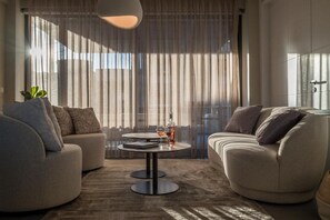 A modern living room with two sofas, a coffee table, and a large window with sheer curtains. - Urban Living Home with Jacuzzi (Agios Onoufrios)