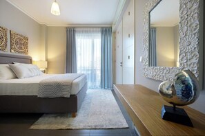 A bedroom with a bed, a bedside table, a mirror, and a decorative wall piece. - Urban Living Home with Jacuzzi (Agios Onoufrios)