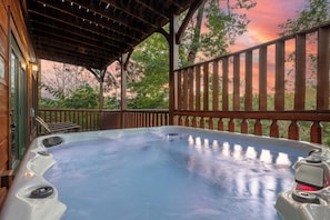 A hot tub under a wooden pergola with a view of trees and a sunset. - Bear Cave | Theater, Arcade & Hot Tub | 3 King Suites | Sleeps 10 (Gatlinburg)