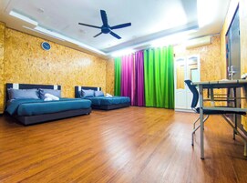 A room with two beds, a ceiling fan, a desk, and a chair.