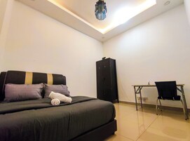 A bedroom with a bed, a desk, and a wardrobe.