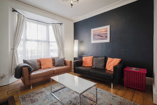 A living room with two sofas, a coffee table, a lamp, and a picture on the wall. - Comfortable 3 Bedroom Townhouse Sleeps 6 (Northampton)