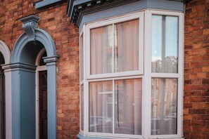 A corner bay window with white framing and a brick wall. - Comfortable 3 Bedroom Townhouse Sleeps 6 (Northampton)