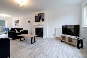 Ein modernes Wohnzimmer mit Kamin, Flachbildfernseher und Essbereich.