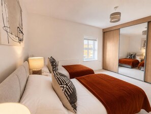 A bedroom with a bed, a bedside lamp, a window, and a mirror. - The Urban Nest – Stylish Hoole Stay for 4 (Cheshire West and Chester)