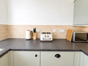 Een keuken met een broodrooster, een waterkoker en een magnetron op het aanrecht.