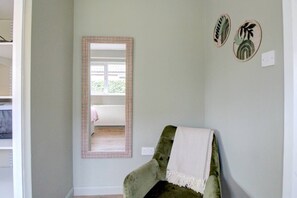 Ein Zimmer mit einem grünen Sessel, einem Spiegel und zwei Wandbildern.