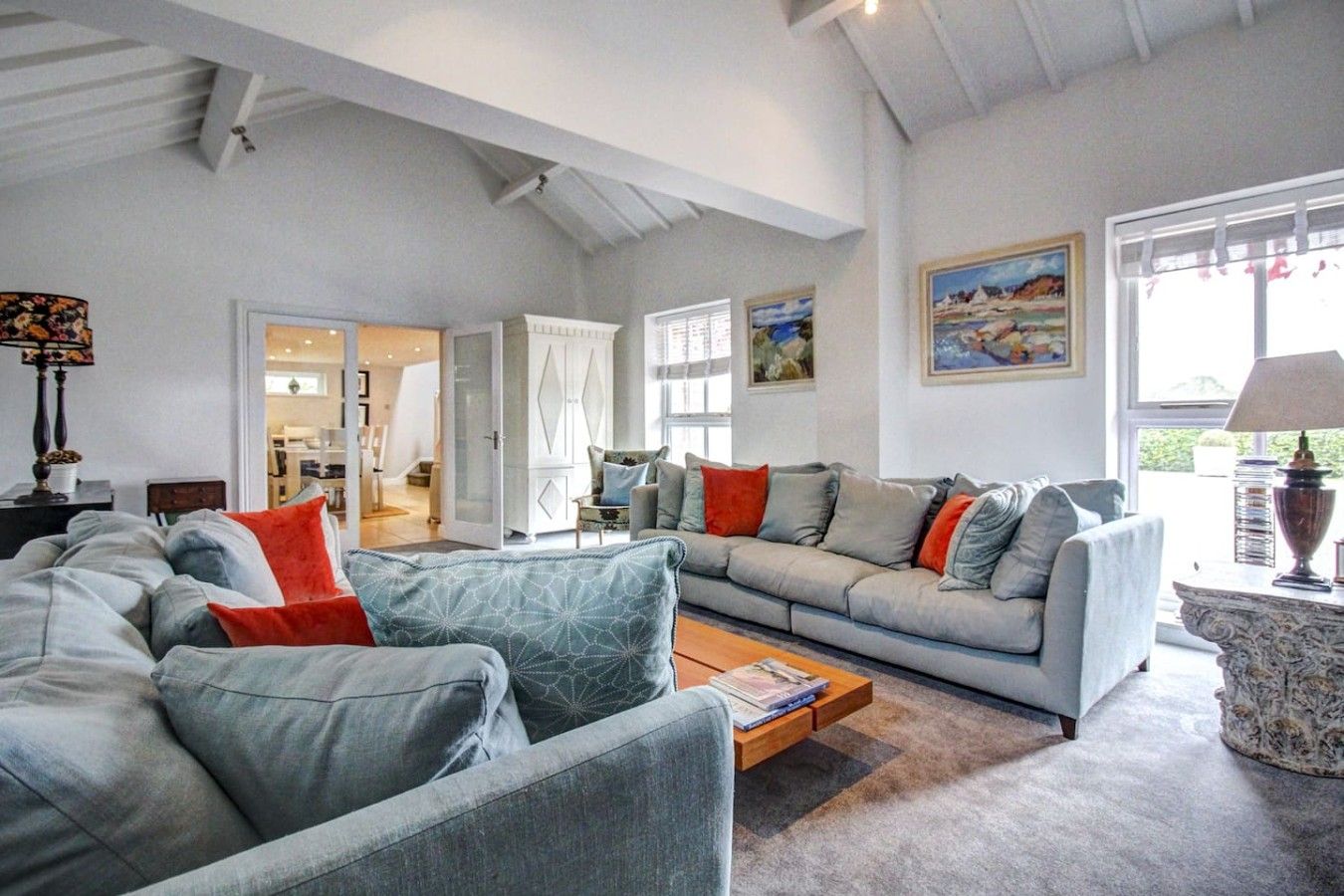 A spacious living room with a grey sofa set, a coffee table, and a bookshelf.