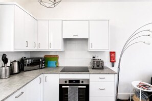 Eine moderne Küche mit weißen Schränken, einer Mikrowelle, einem Toaster und einem Geschirrspüler.