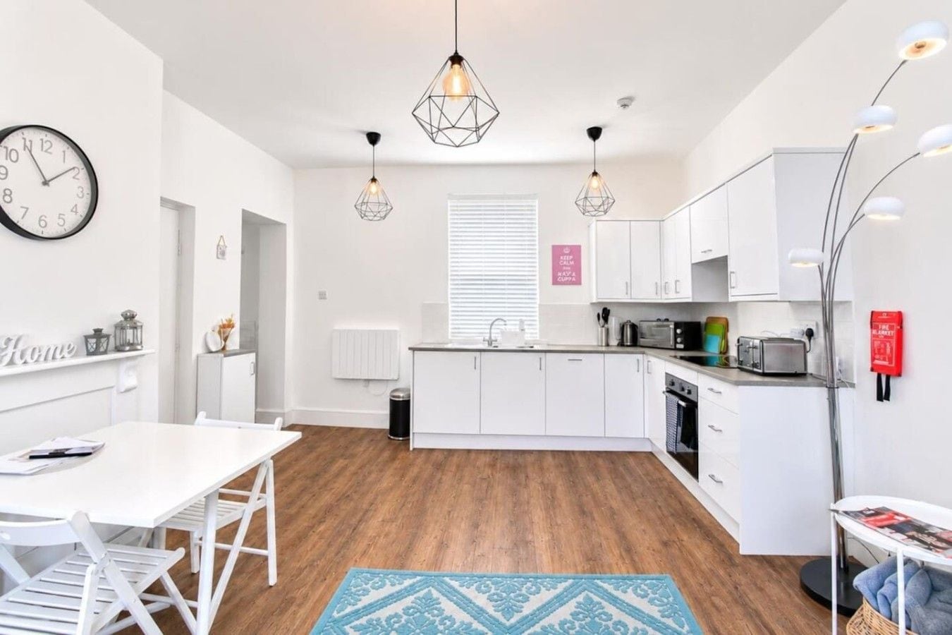 Una cocina moderna con armarios blancos, una isla central e iluminación colgante.
