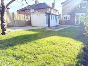 A residential area with a grassy yard, a detached garage, and a brick house with a chimney. - The Family Holiday in Chester, Parking and Garden (Cheshire West and Chester)