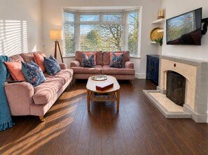 A living room with two sofas, a coffee table, a fireplace, and a television. - The Family Holiday in Chester, Parking and Garden (Cheshire West and Chester)