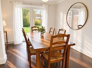 A dining room with a wooden table and chairs, a potted plant, and a mirror on the wall. - The Family Holiday in Chester, Parking and Garden (Cheshire West and Chester)