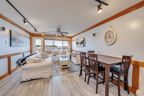 A spacious living area with a white sofa, a dining table with chairs, and a ceiling fan. - Victory Hull  - Bayfront Condo in the Heart of Stone Harbor, NJ (Stone Harbor)
