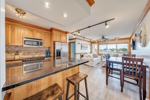 Een moderne keuken met houten kastjes, een groot eiland en een eethoek met een tafel en stoelen.