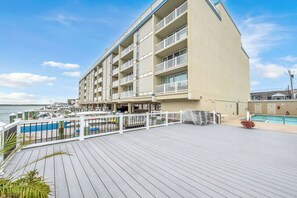 A hotel with a pool area, outdoor seating, and a view of the water. - Victory Hull  - Bayfront Condo in the Heart of Stone Harbor, NJ (Stone Harbor)