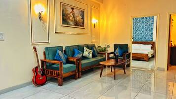 Een hotel lobby met een zithoek, een bijzettafeltje, een gitaar en een schilderij aan de muur.