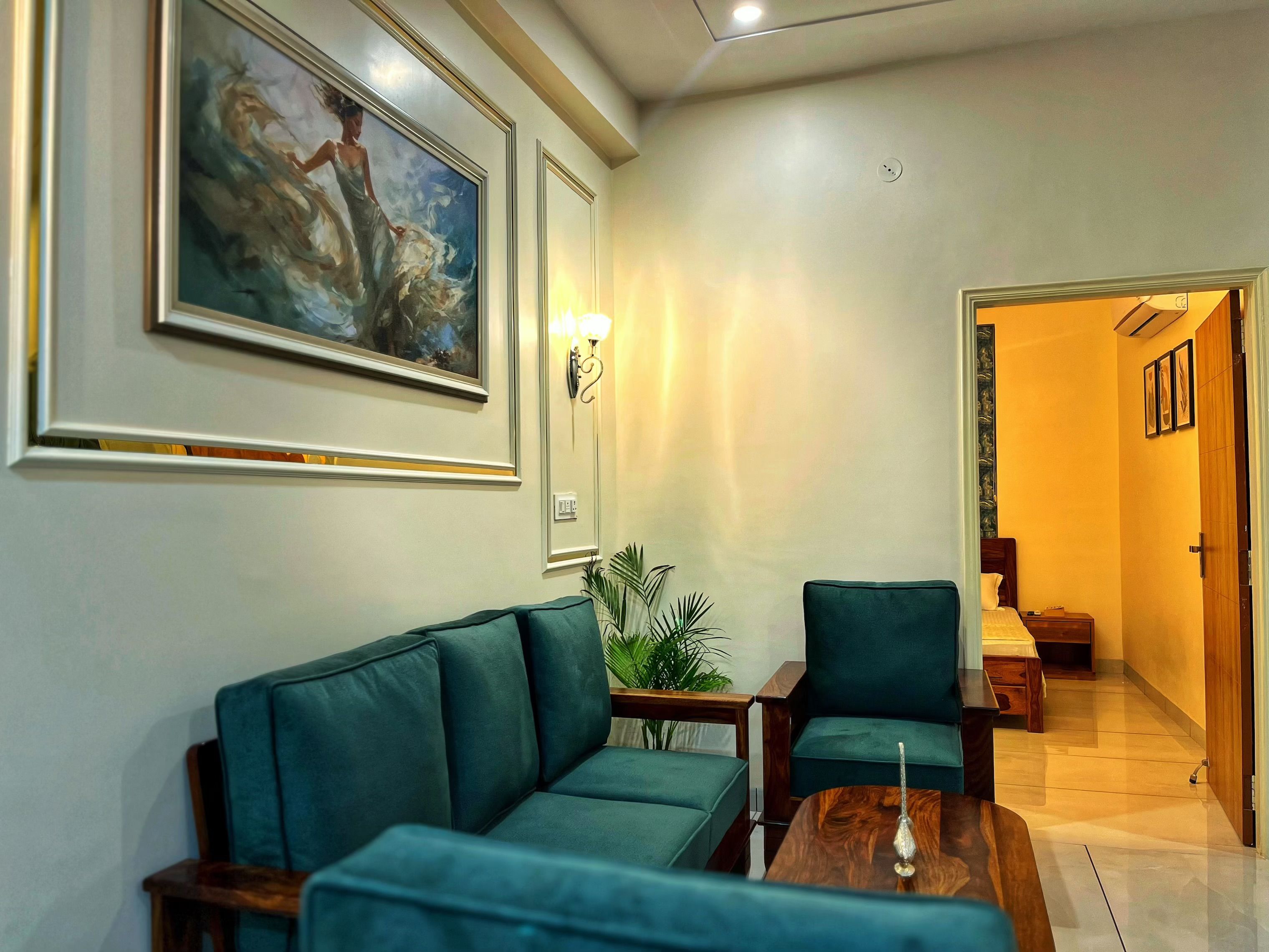 A modern living room with a teal sofa, a wooden coffee table, and a painting on the wall.