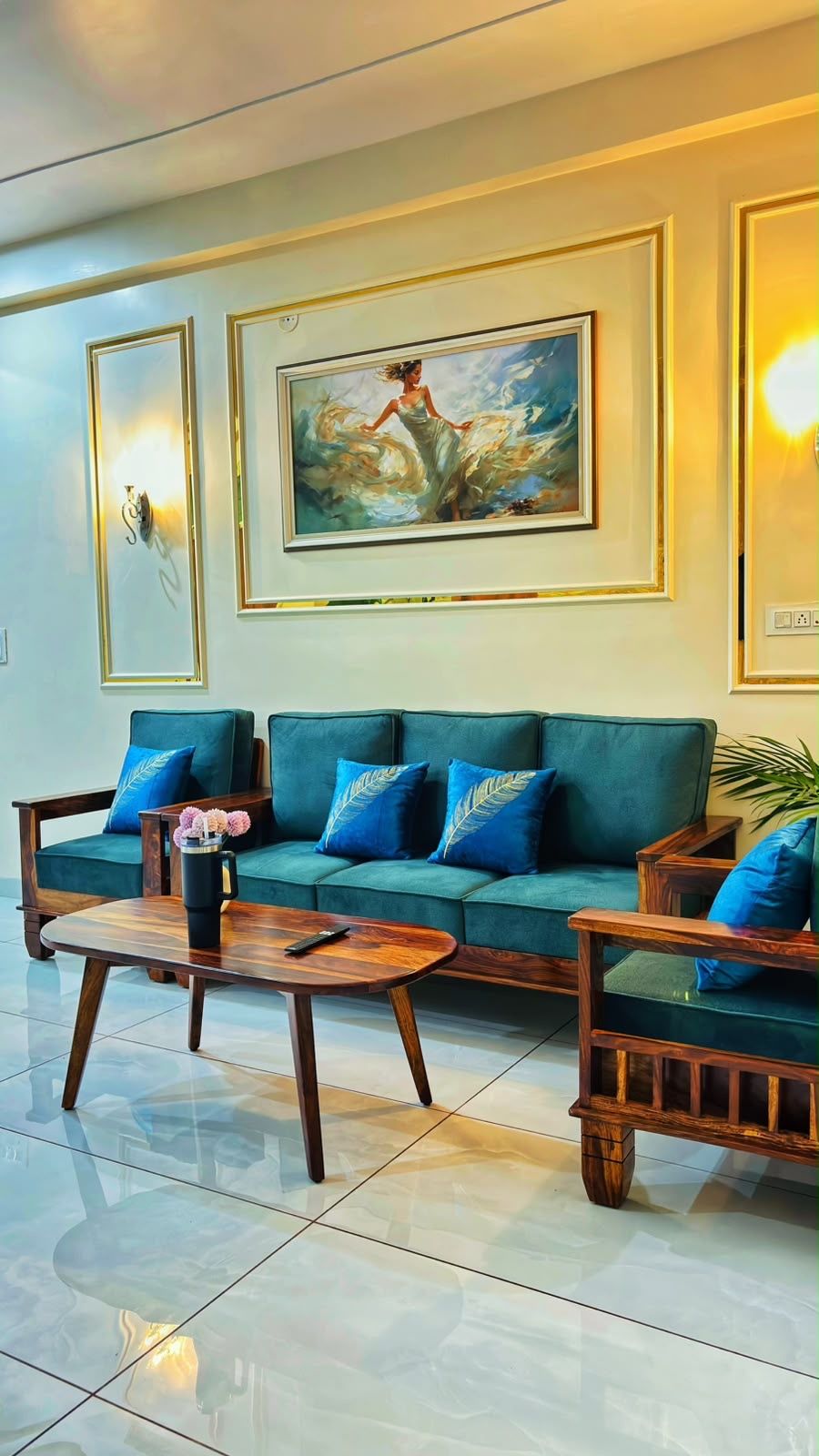 Ein modernes Wohnzimmer mit einem grünen Sofa, Holzsesseln, einem Couchtisch und einem Bild an der Wand.