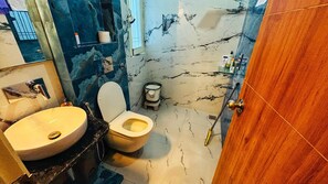 Een badkamer met een marmeren vloer, een toilet, een wastafel en een houten deur.