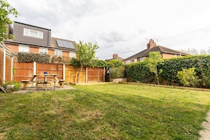 A residential backyard with a wooden fence, a picnic table, and a grassy lawn. - Barbridge Canal Holiday (Cheshire East)