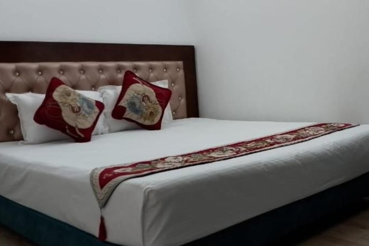 A hotel room with a bed, a bedside table with a phone, and a chair.