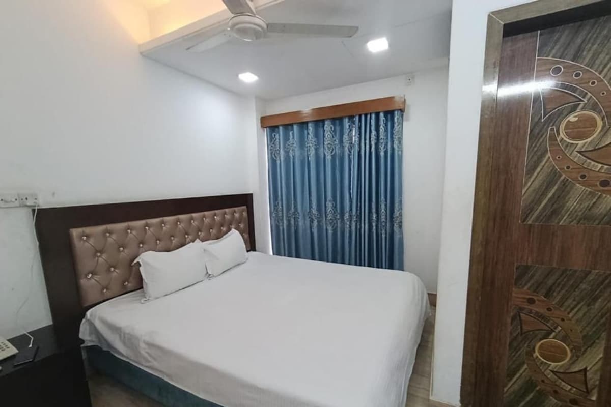 A bedroom with a bed, a nightstand, a ceiling fan, and a wooden door with a decorative design.
