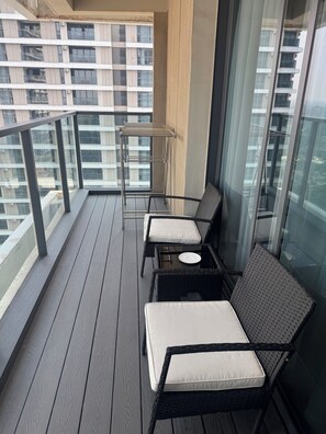 A balcony with wicker furniture, a small round table, and a metal drying rack. - Elegant 2-Bedroom Luxury Retreat at GTC Residency (Nairobi)