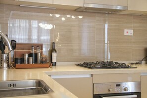 A modern kitchen with a stainless steel sink, a built-in oven, and a gas stove. - Elegant 2-Bedroom Luxury Retreat at GTC Residency (Nairobi)