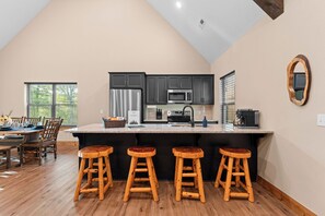 Une cuisine moderne avec des meubles de couleur sombre, des appareils en acier inoxydable et un îlot central doté de tabourets.