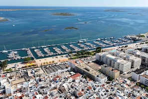 A marina with numerous boats docked, a coastal town with compact buildings, and a clear view of the sea. - Stylish Apartament in the Heart of Olhao, Algarve (Olhão)