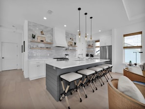 A modern kitchen with a central island, bar stools, and pendant lighting. - Golden Palms at St. Augustine | Luxury, Pool + Nearby Beach Access (St. Augustine)