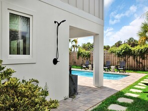 A house with a covered patio area, a swimming pool, and a wooden fence in the background. - Golden Palms at St. Augustine | Luxury, Pool + Nearby Beach Access (St. Augustine)