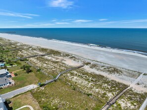 Un paisaje costero con una playa, un muelle y una carretera que conduce a un edificio.