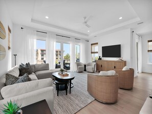 A modern living room with a sofa, armchairs, a coffee table, and a TV. - Golden Palms at St. Augustine | Luxury, Pool + Nearby Beach Access (St. Augustine)