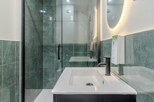 Un baño moderno con cabina de ducha de vidrio, un lavabo blanco y un espejo.