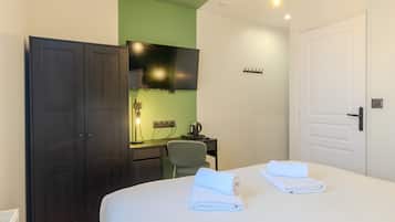 A hotel room with a bed, a desk, a chair, a wardrobe, and a television.