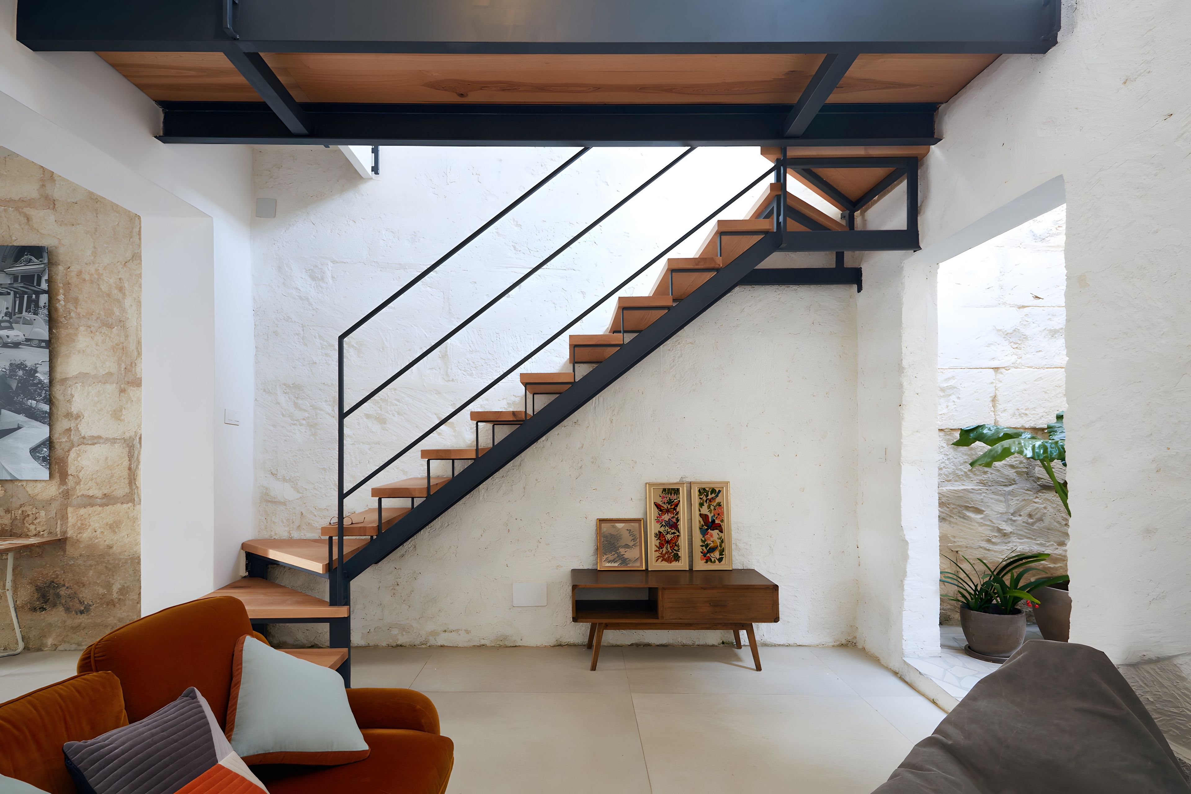 Un intérieur moderne avec un escalier, un canapé et une petite table agrémentée d’objets décoratifs.