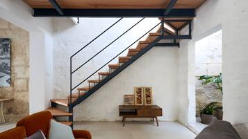 Un intérieur moderne avec un escalier, un canapé et une petite table agrémentée d’objets décoratifs.
