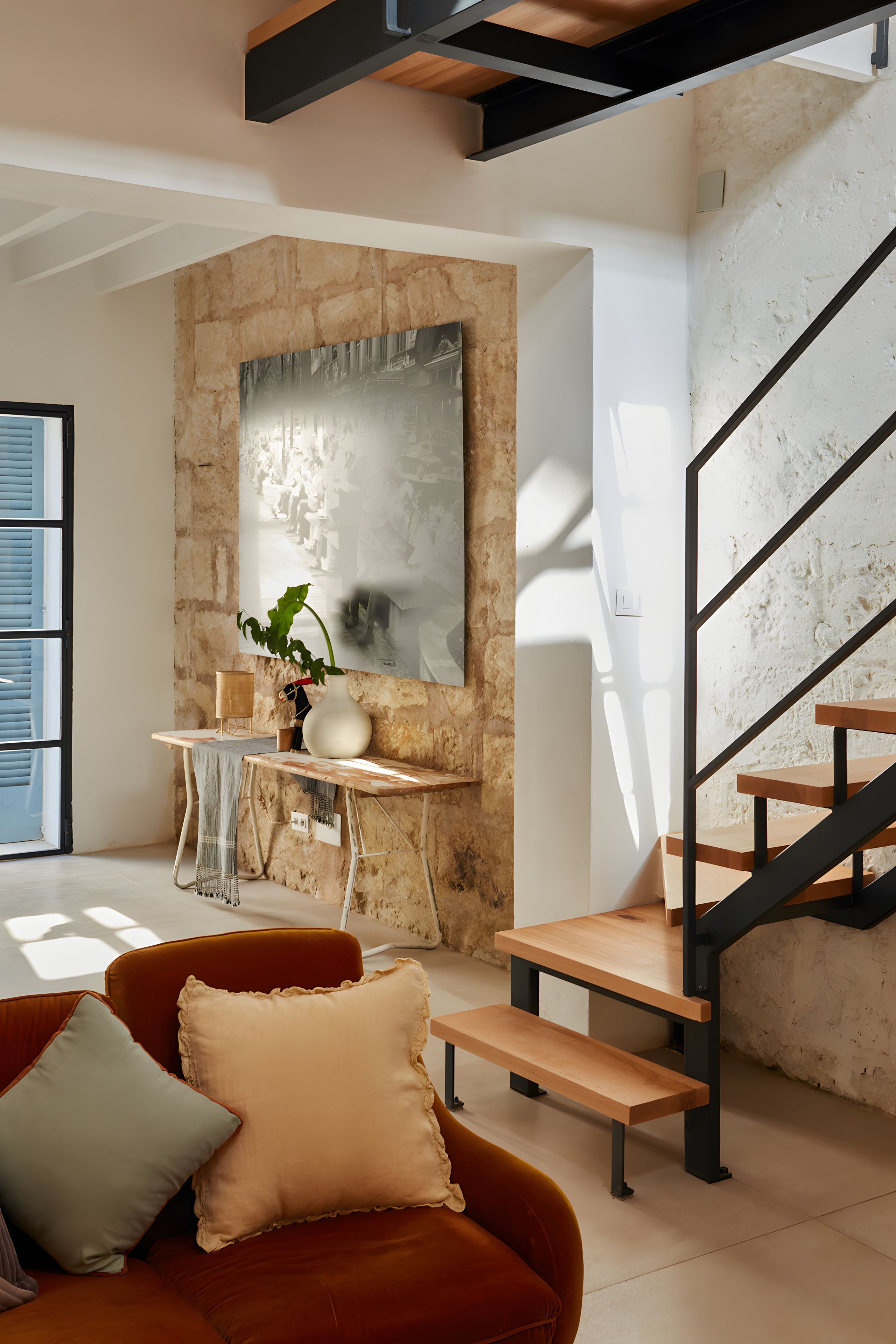 Et moderne interiør med trappe, sofa og et bord med en vase.