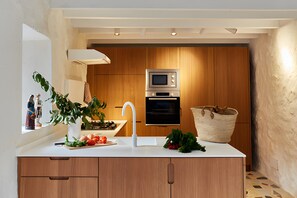 Una cocina moderna con armarios de madera, encimera blanca, horno empotrado y microondas.