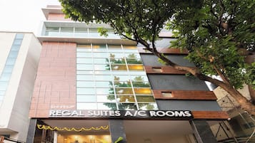 A hotel with a sign for 'Regal Suites A/C Rooms' and a modern architectural design.