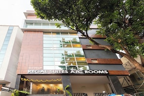 A hotel with a sign for 'Regal Suites A/C Rooms' and a modern architectural design. - Capital O Regal suites (Bangalore)