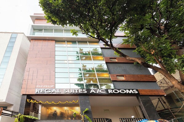 Un hôtel avec une enseigne indiquant « Regal Suites, chambres climatisées » et présentant un design architectural moderne.