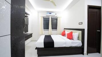 A bedroom with a bed, a ceiling fan, an air conditioning unit, and a window with curtains.