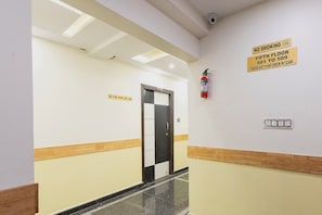 A hotel corridor with a check-in desk, a fire extinguisher, and directional signs for rooms 501 to 509. - Capital O Regal suites (Bangalore)